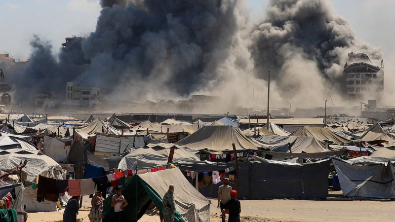 vertriebene Palästinenser:innen in einem Zeltlager Mitte September in Gaza-Stadt, im Hintergrund Staubwolken eines Bombardement