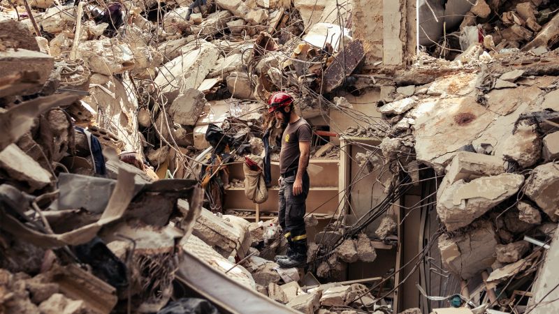 ein Helfer mit Helm steht auf den Trümmern des zerstörten Hauses in Beirut