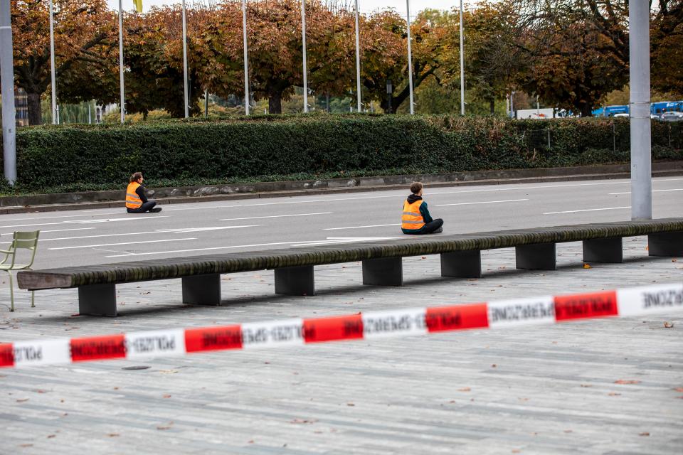 Personen sitzen auf abgesperrter Strasse