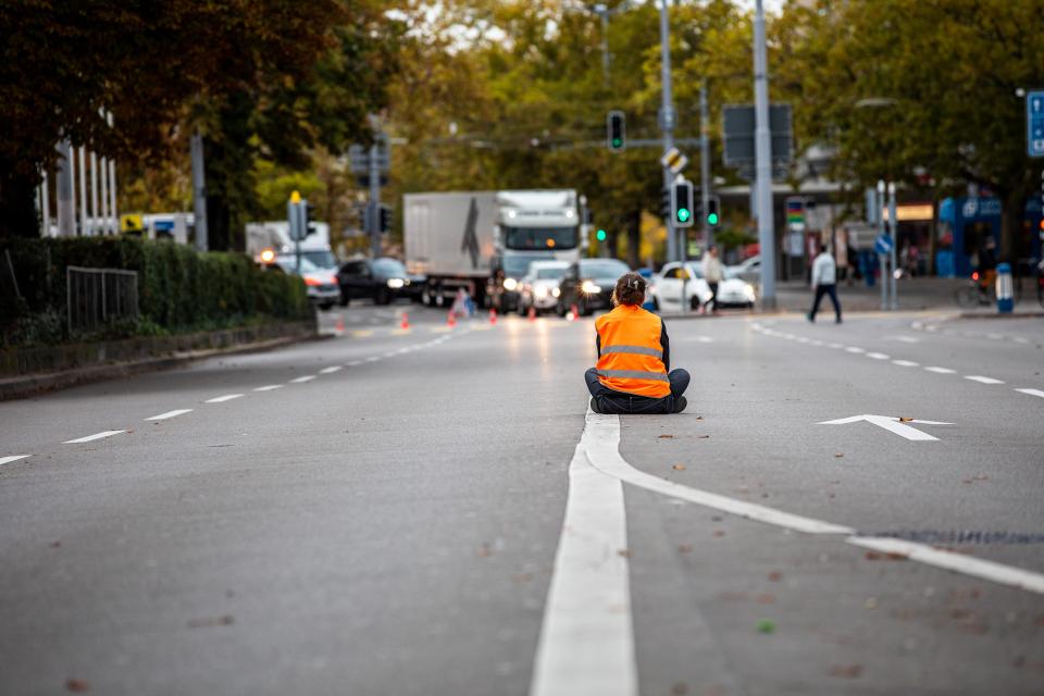 Person sitzt auf abgesperrter Strasse