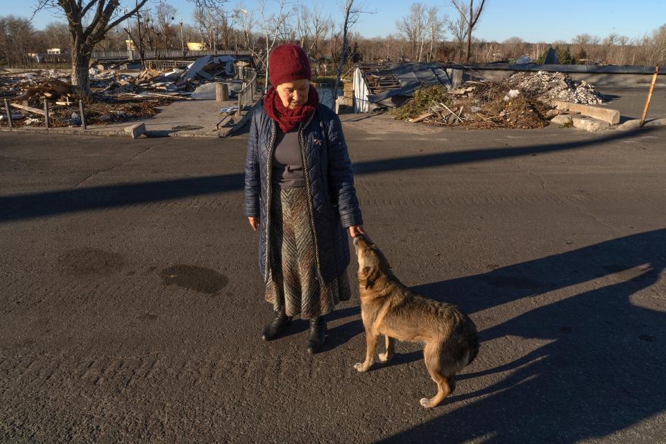 Wera Larina steht vor zerstörten Gebäuden und streichelt einen Hund