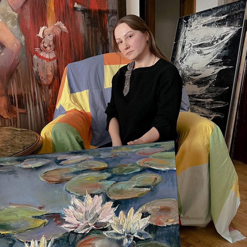 Ludmila Odnovolik sitzt auf einem Sessel, umgeben von Gemälden