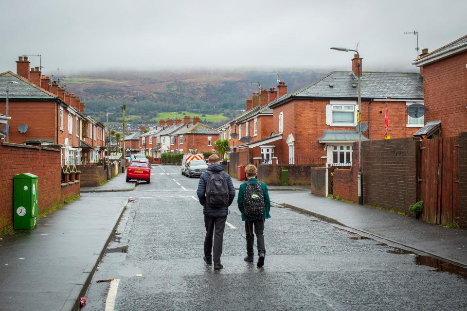 zwei junge Personen in Schuluniform gehen auf einer Quartier-Strasse in Belfast