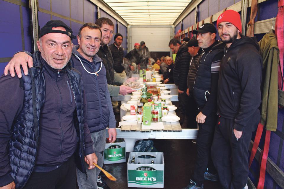 Lastwagen-Chauffeure feiern das Osterfest an einem improvisierten Tisch in einem Lastwagenanhänger