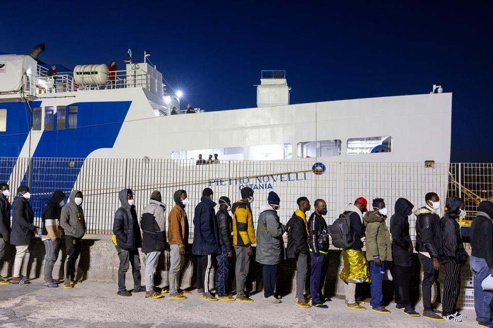 Flüchtende warten vor einem Schiff auf den Transfer nach Sizilien von der Insel Lampedusa