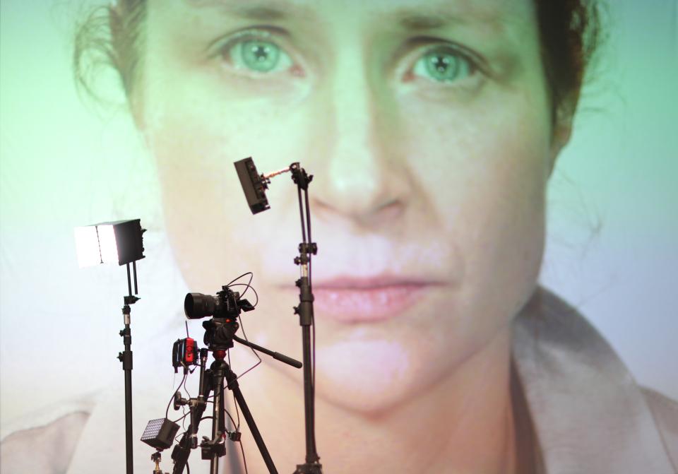 Foto-Equipment welche vor einer Leinwand mit einer Projektion eines Frauengesichts steht