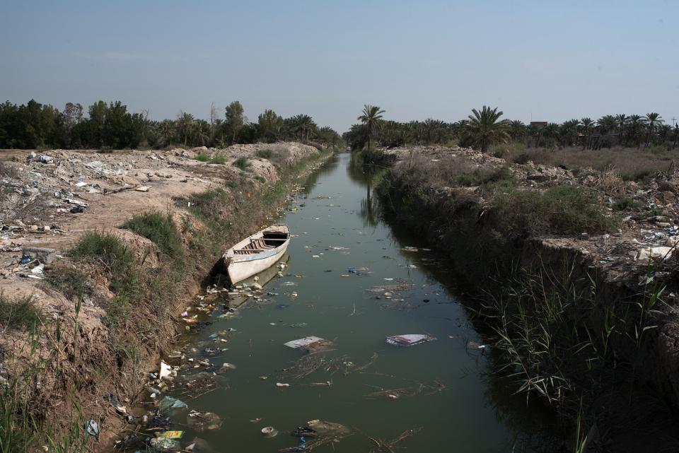 verschmutzter Kanal mit einem Holzboot