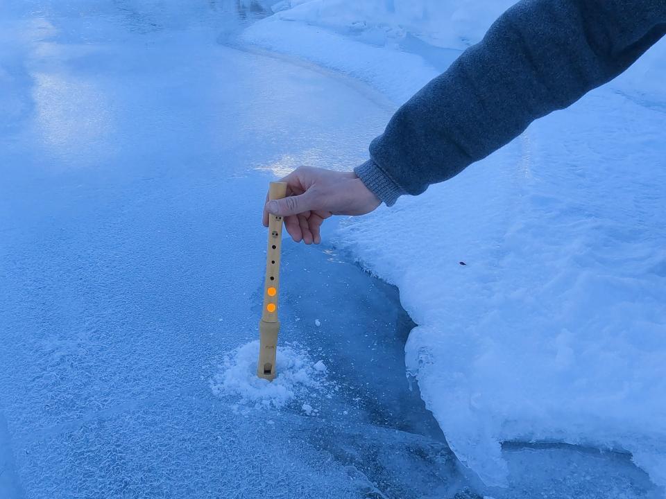 Still aus «Lost Waters and Found Stairs»: eine Person hält eine Blockflöte in ein Loch eines gefrorenes Gewässers