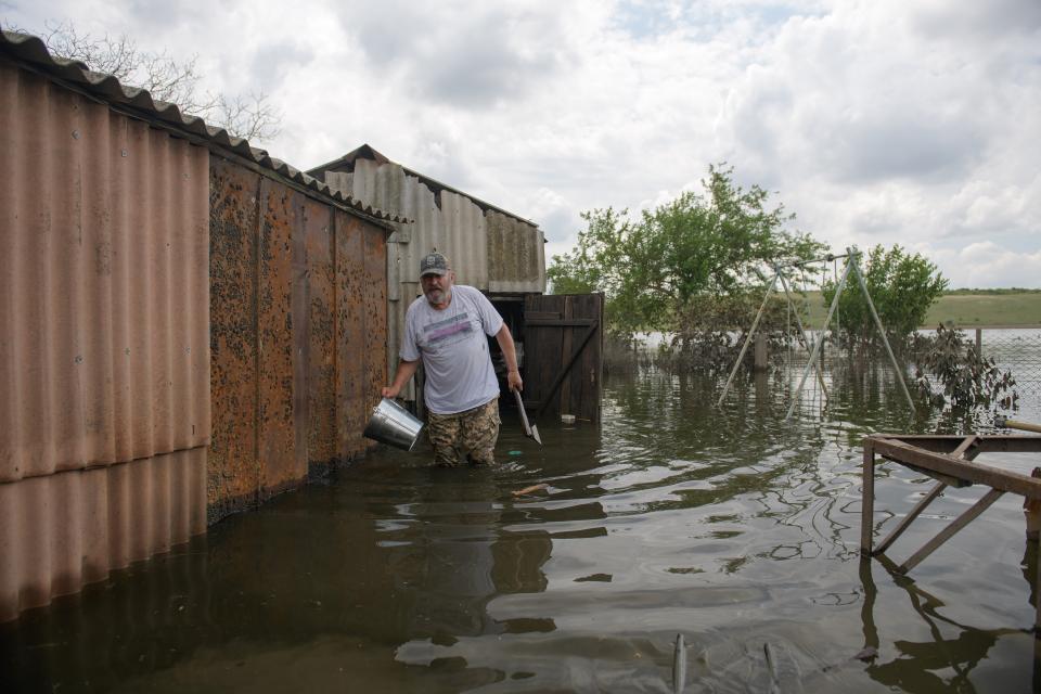 Wolodymyr Saporoschtschenko watet durchs kniehohe Wasser vor einer Scheune