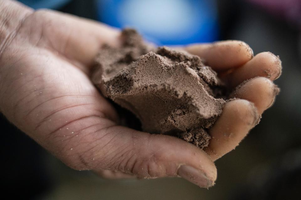 ein Fischer hält Zysten der Artemiakrebse in der Hand, welche aussehen wie Sand