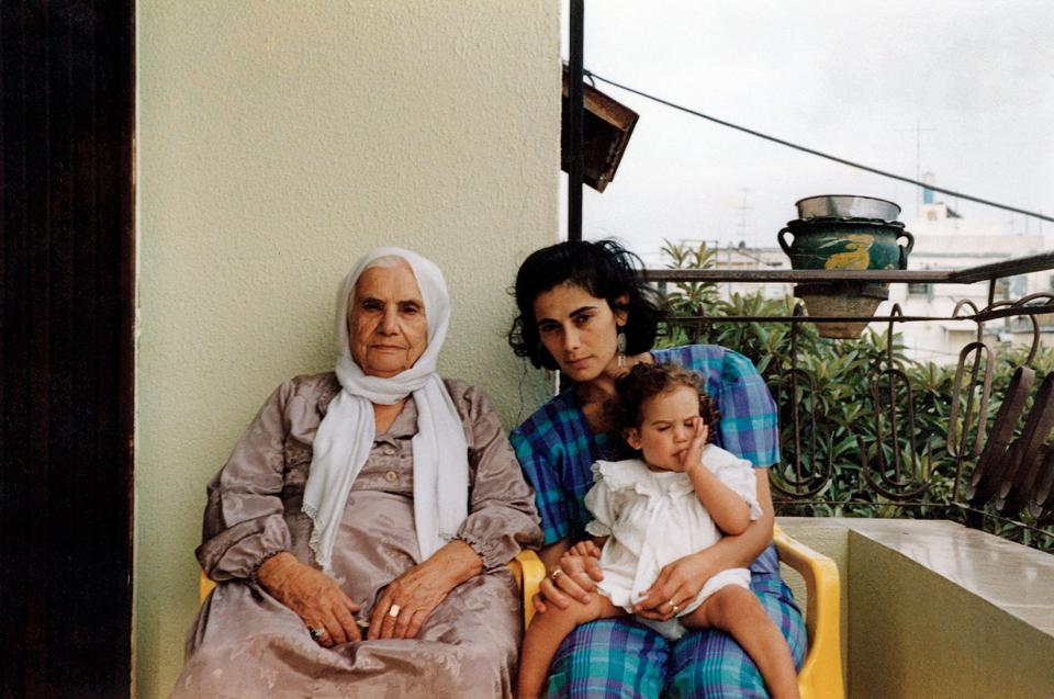 eine ältere Frau und eine jüngere Frau mit Kind sitzen auf einem Balkon