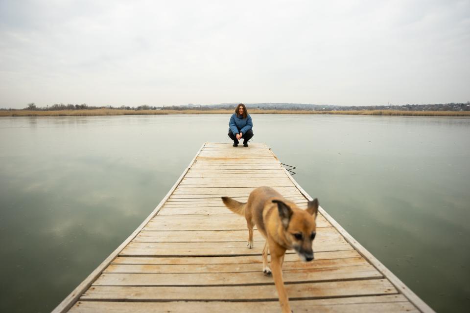 Viktoria Rythenko mit ihrem Hund auf einem Steg an einem Seeufer