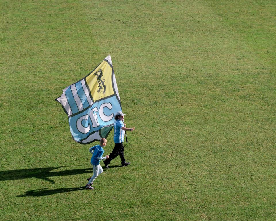 Fans des Chemnitzer FC mit einer Fahne auf dem Spielfeld vor dem Heimspiel gegen BSG Chemie Leipzig