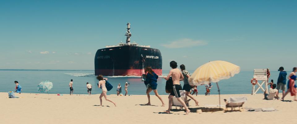 Filmstill aus «Leave the World Behind»: ein Supertanker fährt auf einen Badestrand zu, Menschen am Badestrand flüchten