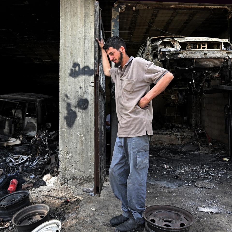 Muhammad Abu Aliya inmitten seiner ausgebrannten Autowerkstatt