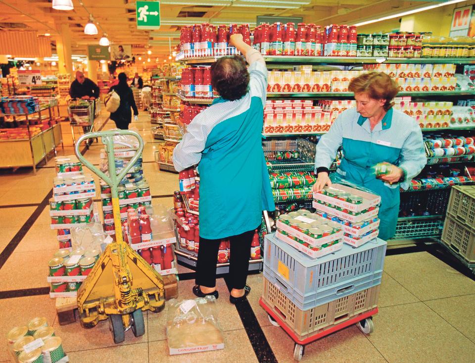 Angestellte in einer Migros-Filiale räumen Gestelle ein