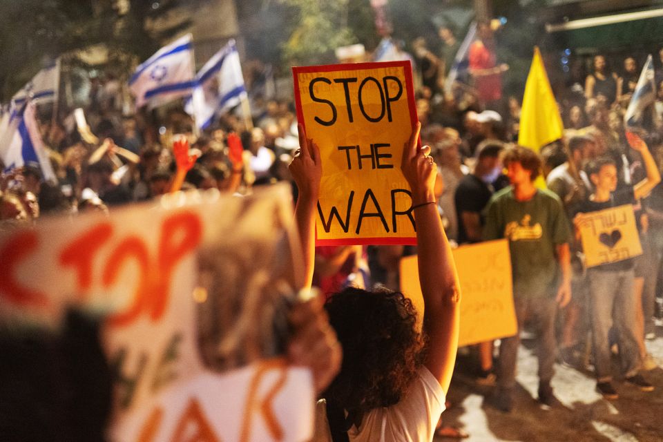 eine Demo-Teilnehmerin hält ein Schild mit dem Text «STOP THE WAR» in die Höhe