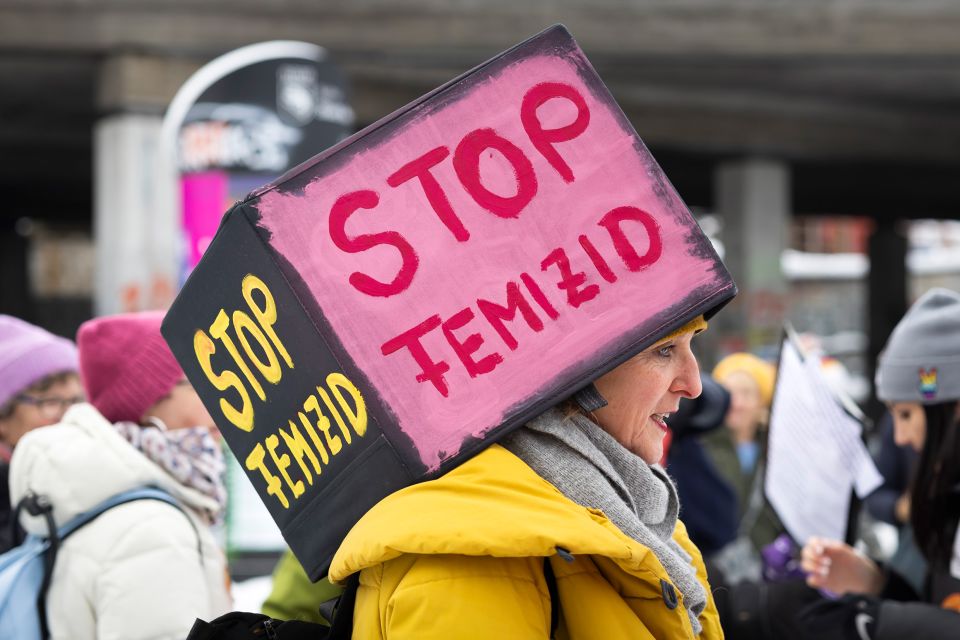 eine Frau mit einem Würfel auf dem Kopf mit dem Text «STOP FEMIZID»