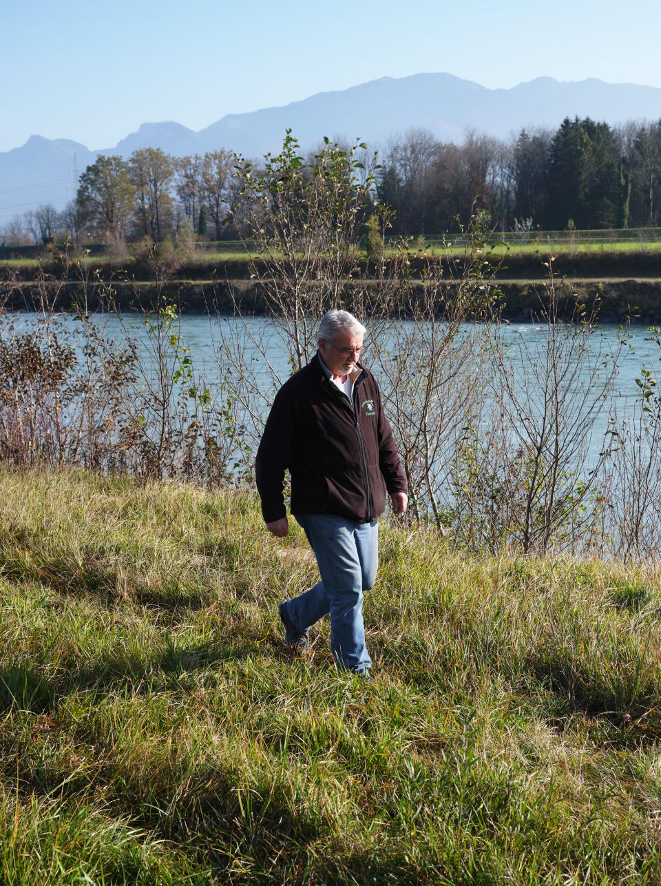 Bauer Hans Graf läuft auf einer Wiese dem Rhein entlang