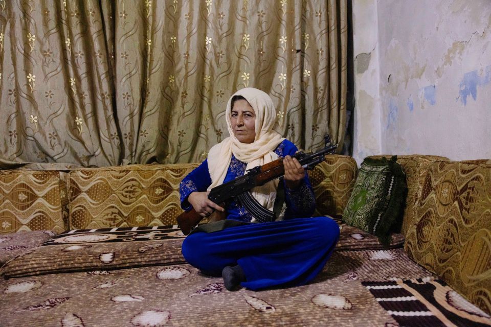 Hawar Barawad sitzt mit einem Gewehr am Boden