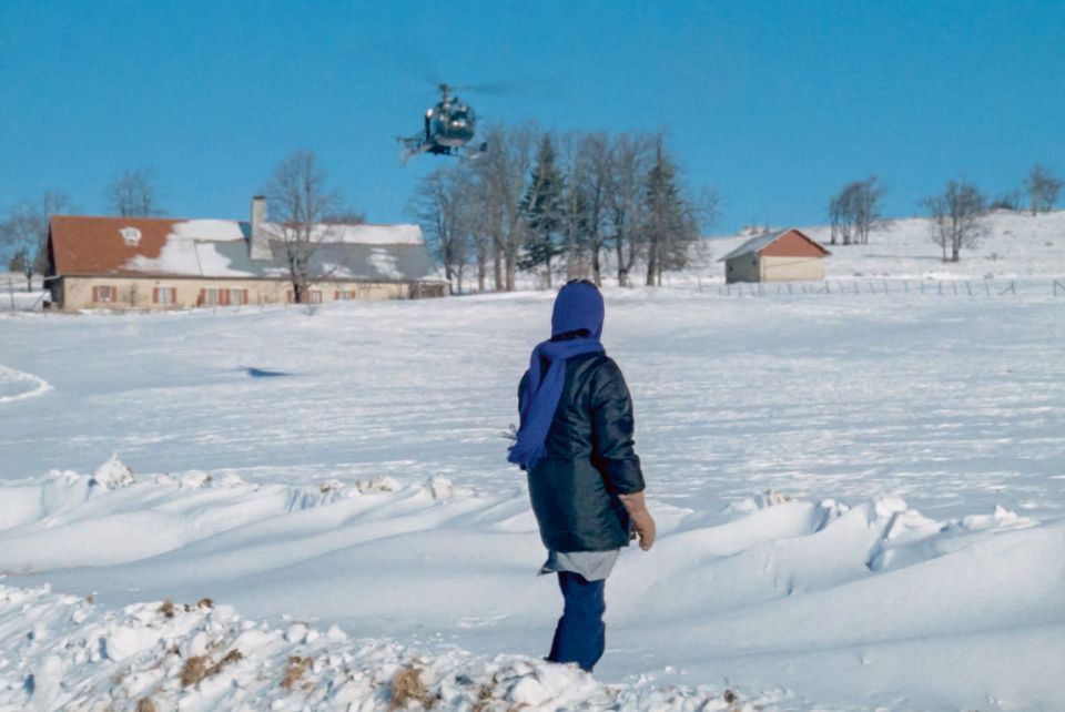 Filmstill aus «Les granges brûlées»: eine Frau steht im Schnee und schaut auf einen Helikopter in der Luft