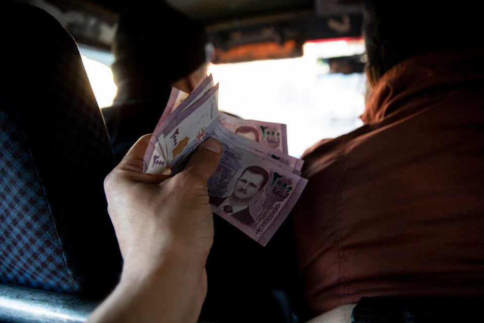 eine Passagier:in überreicht Abu Muhammad Geld für die Kleinbus-Taxifahrt