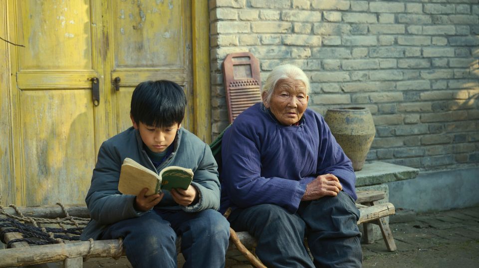 Filmstill aus «Living the Land»: der zehnjährige Chuang sitzt mit einer alten Frau auf einer Bank