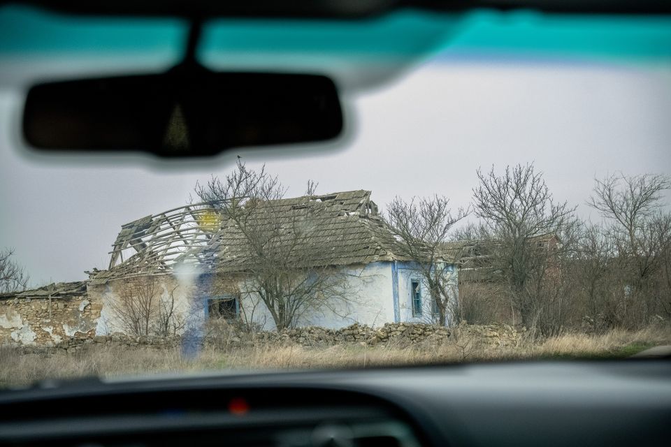 ein zerstörtes Haus fotografiert durch die Windschutzscheibe