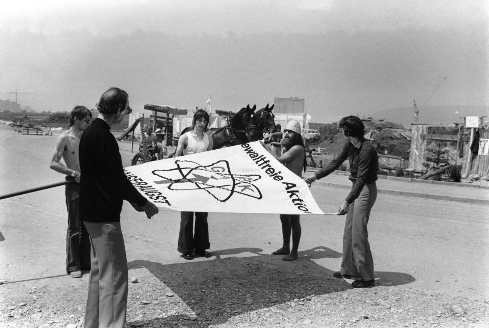 mehrere Personen rollen gemeinsam eine grosse GAK-Flagge ein