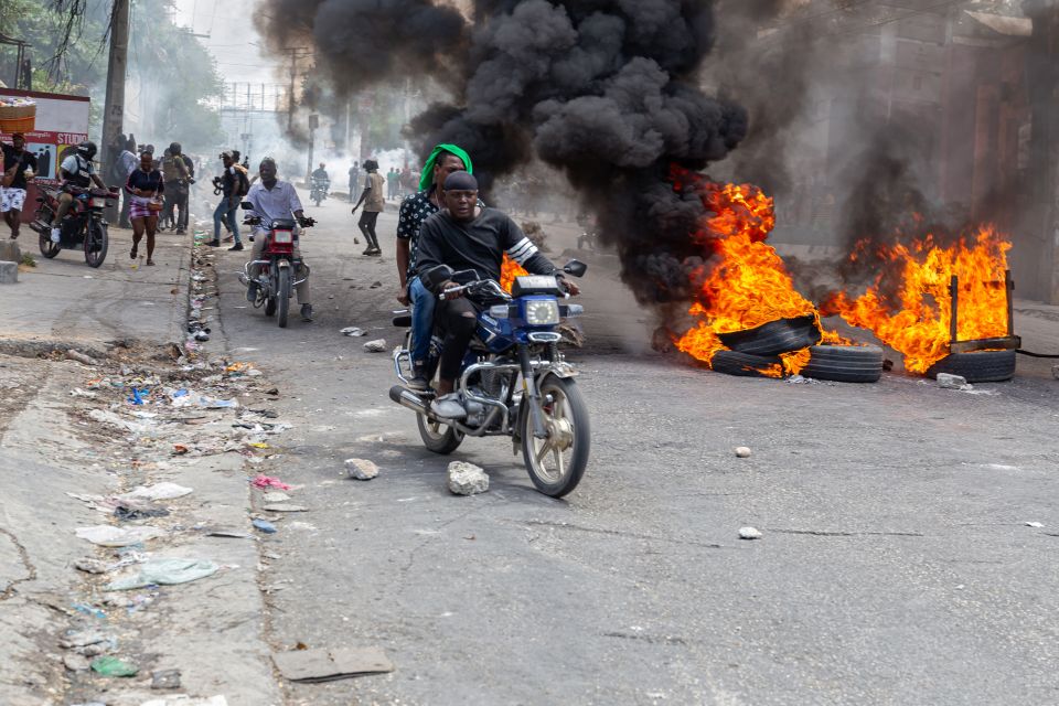 Menschen auf Motorrollern und brennende Reifen bei einem Protest gegen die Bandengewalt in Port-au-Prince am 26. März