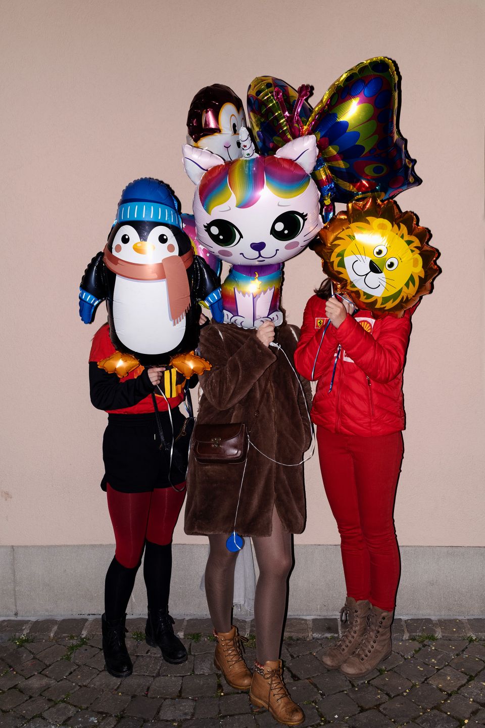 3 Personen halten sich Fantasiefiguren-Luftballons vors Gesicht