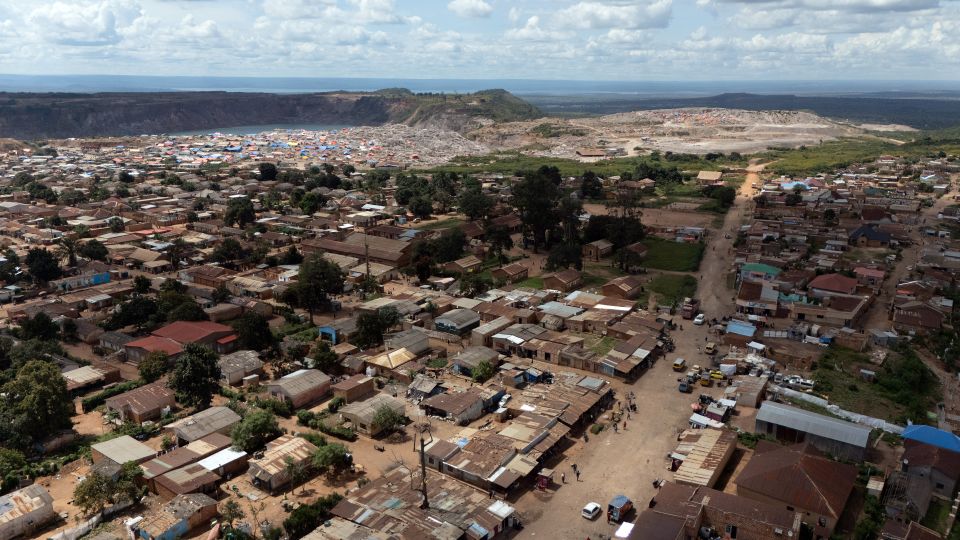 Luftaufnahme einer grossen Siedlung mit Hütten in Kolwezi vor einer Mine