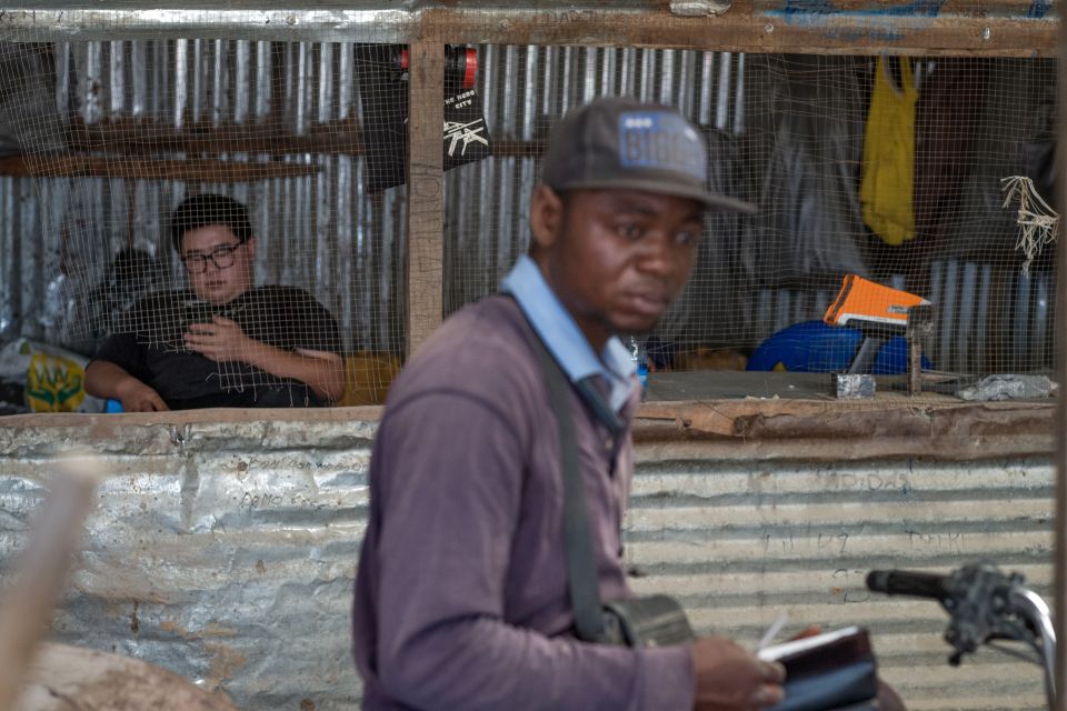 ein chinesischer Mitarbeiter spielt am Ankaufstand Nr. 7 an einer Mine für Kleinmineure in Kolwezi mit seinem Handy