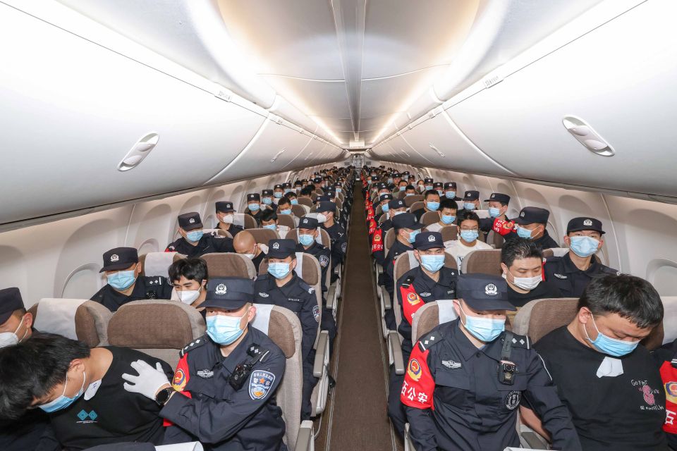 Chinesische Volkspolizisten mit 130 wegen Cyberdelikten Verhafteten in einem Flugzeug