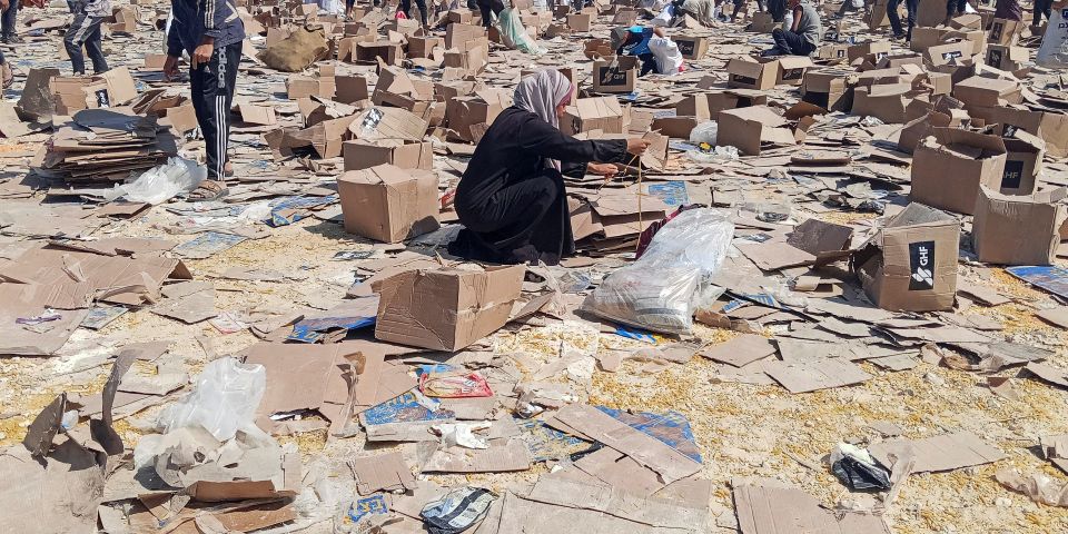 Palästinenser:innen suchen nach der Abgabe von Hilfsgütern in einem GHF-Zentrum in Rafah nach verwertbaren Resten
