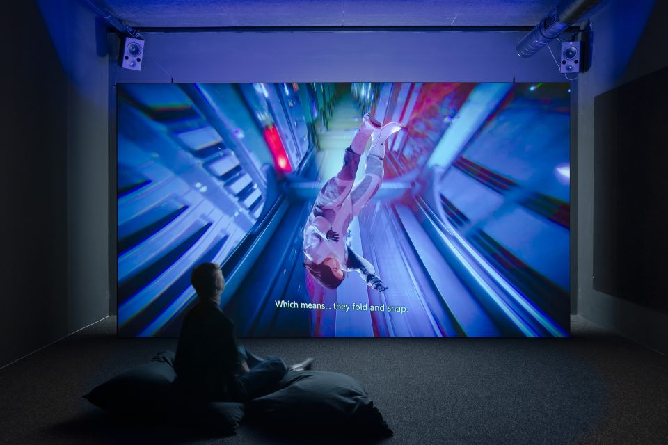 Projektion von Ayoung Kims Video «Delivery Dancer’s ­Sphere» an eine Wand, davor sitzt eine Person am Boden