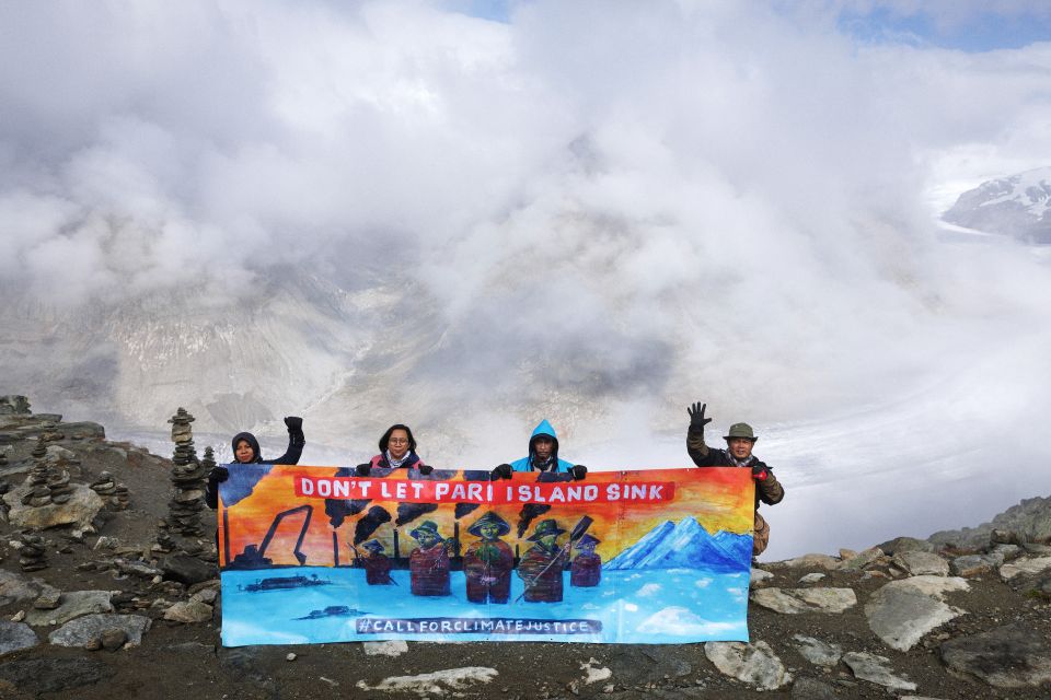 Ibu Asmania und Arif Pujianto halten ein Transparent vor dem Panorama des Aletschgletscher