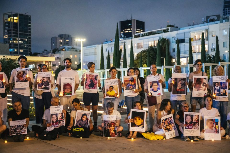 Protestierende stehen schweigend mit Schildern auf denen getötete Kinder zu sehen sind auf dem Theaterplatz in Tel Aviv