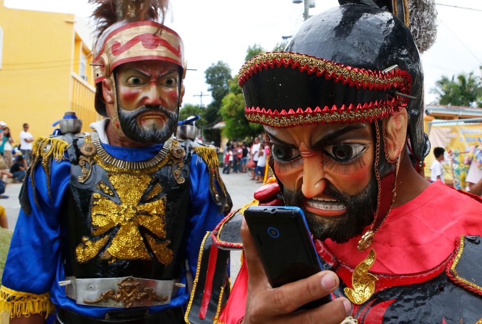 als Römer verkleidete Büsser starren auf ein Smartphone während der Karwoche auf Marinduque, Philippinen