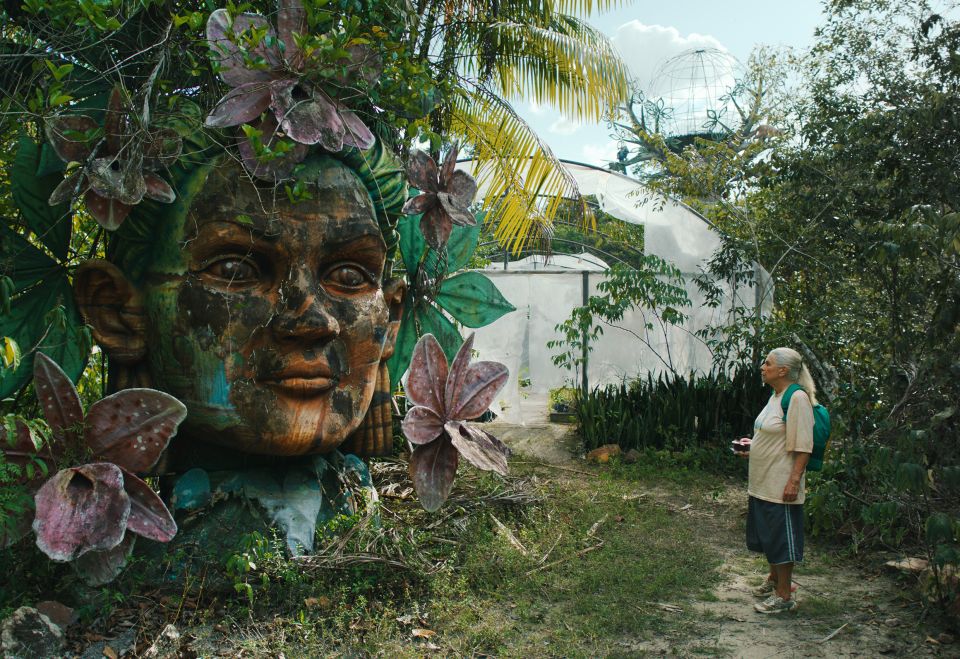 Filmstill aus «Tereza. O último azul»: Denise Weinberg als Alligatorfleischfabrikarbeiterin Tereza steht neben einer Statue