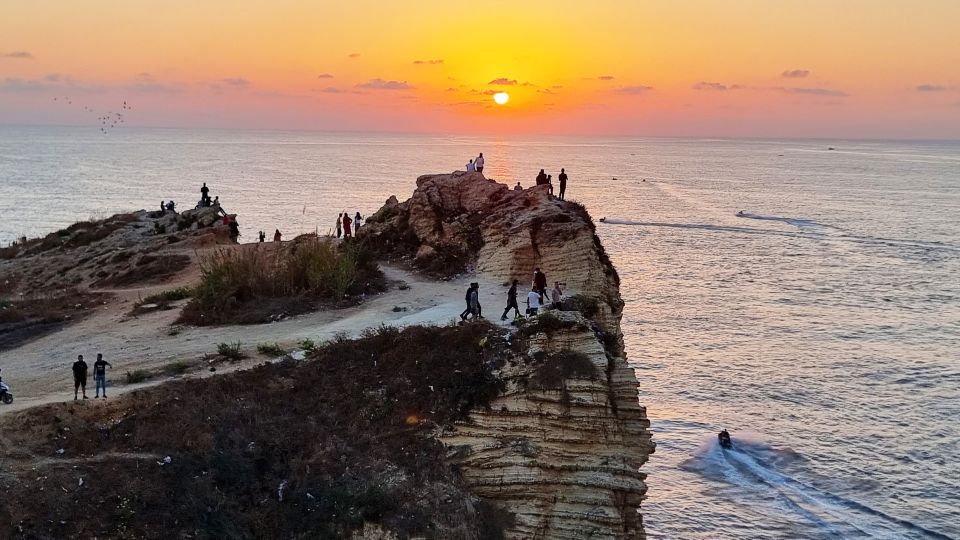 Menschen beim Sonnenuntergang bei den Felsen der Dalieh