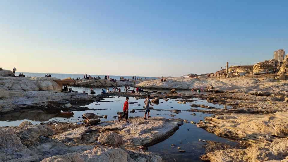 Familien spielen bei den Felsen und Gezeitentümpel der Dalieh am Meer
