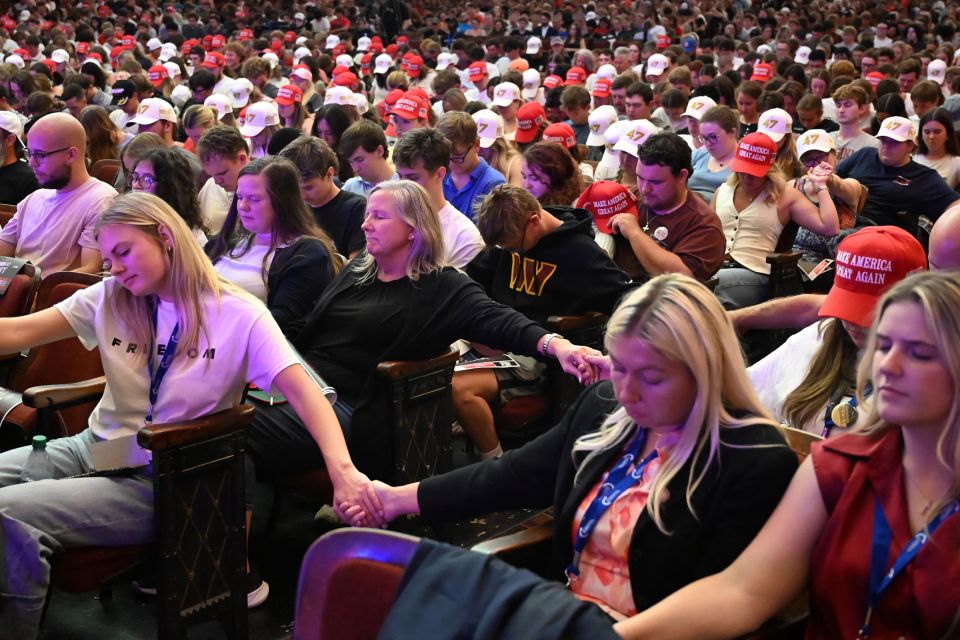 Teilnehmer:innen einer Veranstaltung der Organisation Turning Point USA halten sich an den Hände