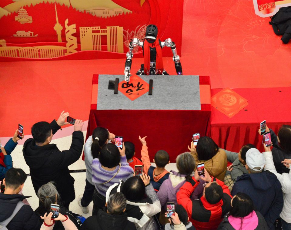Publikum macht Fotos eines KI-gesteuerten Roboter an einer Wissenschaftsmesse in Beijing