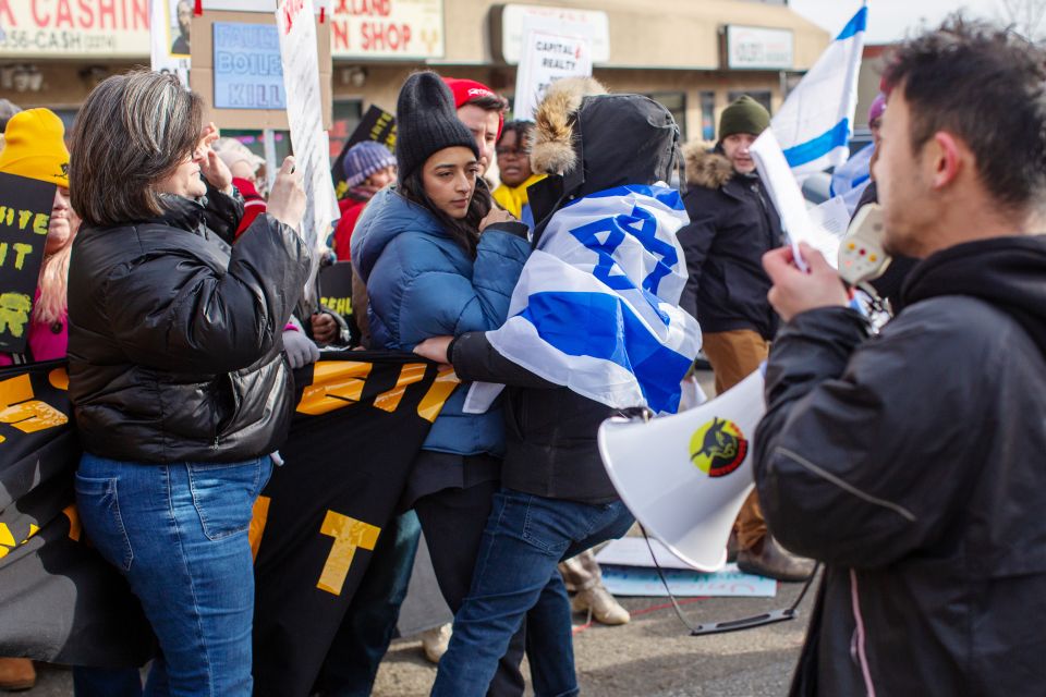 eine Person mit Israel-Fahne versucht Tara Raghuveer ein Transparent zu entreissen