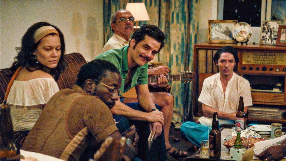 Filmstill aus «The Secret Agent»: eine Gruppe von Menschen sitzt zusammen