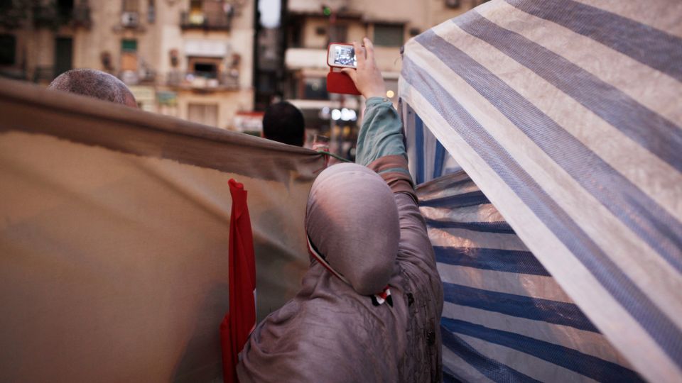 eine Frau hält ein Smartphone in die Höhe um eine Film-Aufnahme zu machen