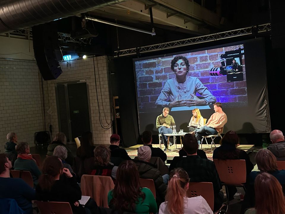  Dominik Gross, Mirjam Hostetmann und Moderator Renato Beck auf der Bühne der Zentralwäscherei, auf der Videoleinwand ist Clara Mattei zu sehen