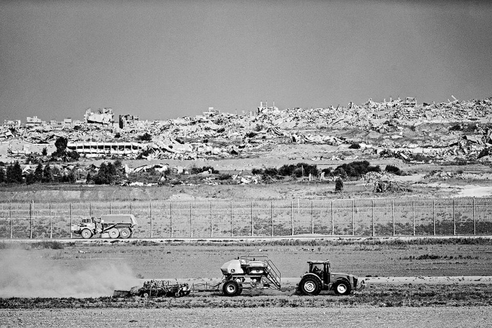 Blick über den Grenzzaun nach Gaza, 30. September 2025: zerstörte Häuser und vor dem Zaun ein Traktor bei der Bodenbearbeitung