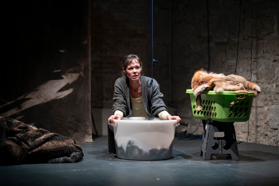 Bühnenfoto des Theaterstück «Zum Beispiel Wölfe. Ach, könnte ich mich auflösen in der Natur»: Mona Petri hält einen grossen Korb in den Händen